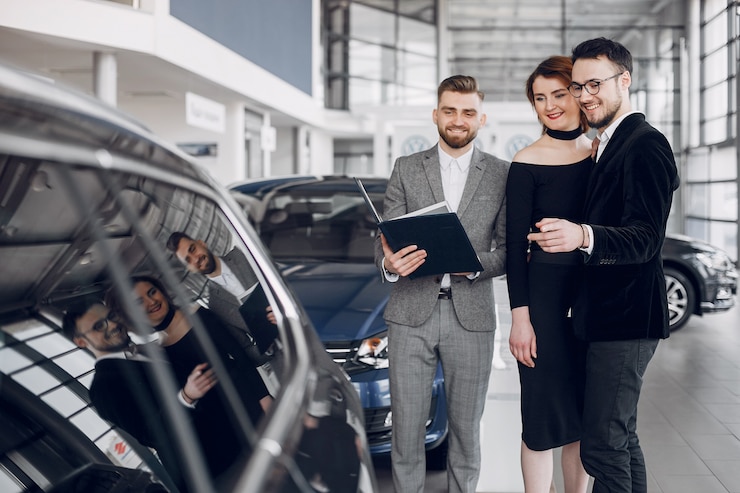 Foto gratuito una pareja elegante y elegante en un salón de automóviles.
