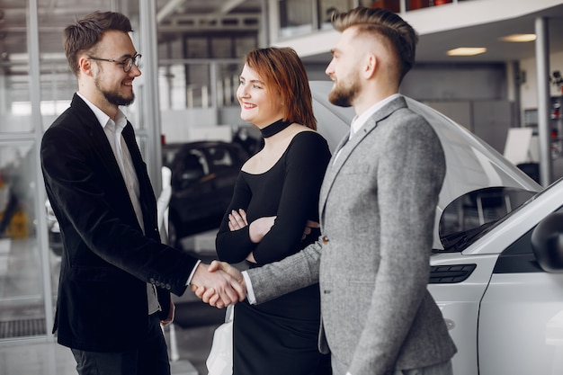 Pareja elegante y elegante en un salón de autos.