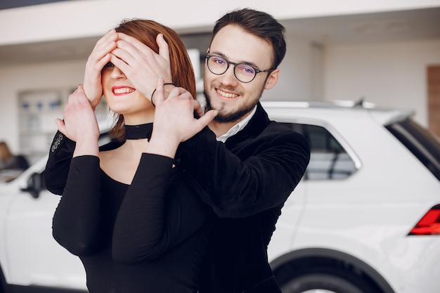 Pareja elegante y elegante en un salón de autos.