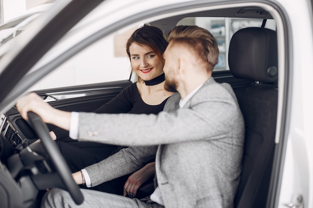 Pareja elegante y elegante en un salón de autos.