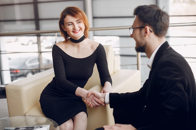 Pareja elegante y elegante en un salón de autos.