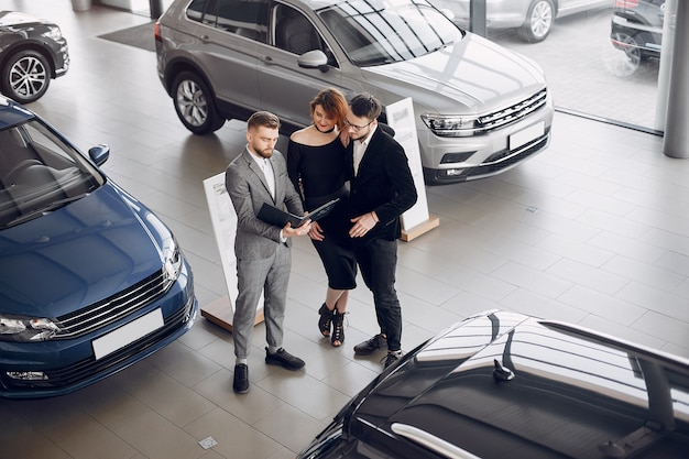 Foto gratuita pareja elegante y elegante en un salón de autos.