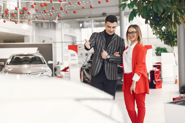 Foto gratuita pareja elegante y elegante en un salón de autos