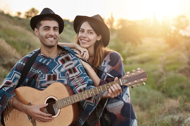 Pareja elegante con guitarra en campo