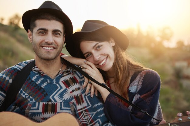 Pareja elegante con guitarra en campo