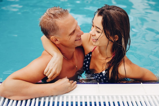 Pareja elegante nadar en la piscina