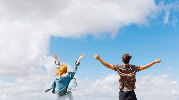 Pareja emocionada y libre con las manos arriba.