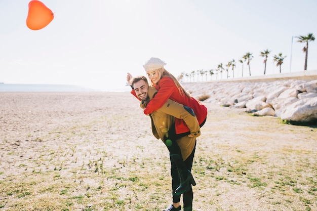 Foto gratuita pareja emocionada posando con globo en la costa
