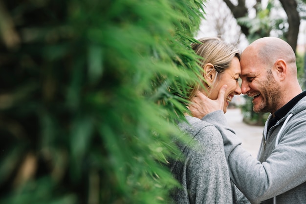 Pareja enamorada detrás de árbol