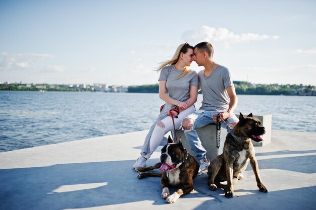 Pareja enamorada de dos perros pit bull terrier contra el lado de la playa