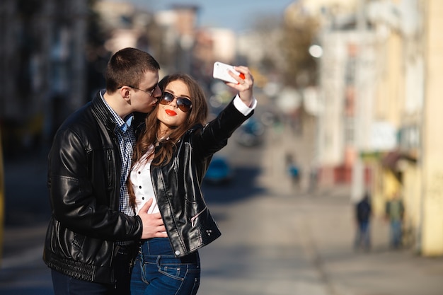 Pareja enamorada haciéndose una foto con la calle de fondo