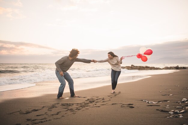 Pareja enamorada jugando y ella con globos en la mano