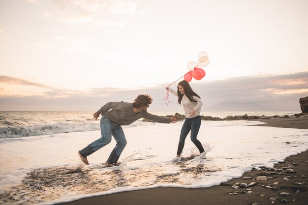 Pareja enamorada jugando y ella con globos en la mano