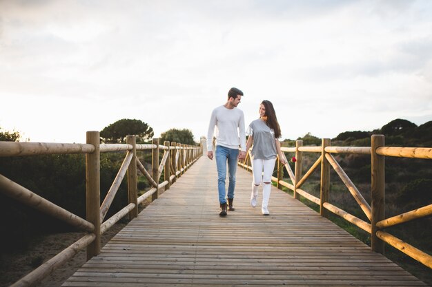 Pareja enamorada paseando por un puente de la mano