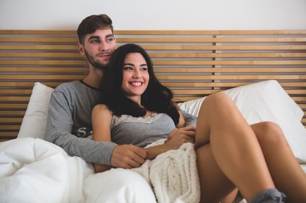 Pareja enamorada tumbada en la cama y abrazada