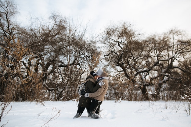 Pareja de enamorados abrazándose de pie en la nieve. Día frío de invierno Winter Love Story.