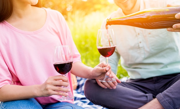 Pareja de enamorados bebiendo vino tinto en picnic