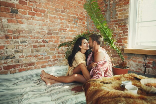 Pareja de enamorados en casa relajándose juntos. Hombre y mujer caucásicos que tienen fin de semana, se ve tierna y feliz. Concepto de relaciones, familia, confort de otoño e invierno. Puras emociones, divirtiéndose.