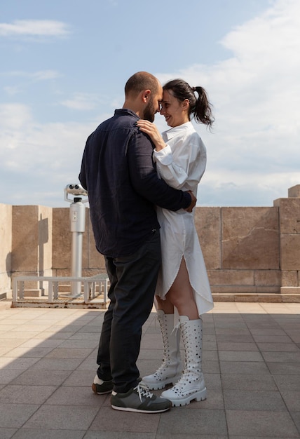 Pareja de enamorados casados abrazándose en la terraza de la torre celebrando el aniversario de la relación disfrutando de la hermosa vista de la ciudad metropolitana. Paisaje con azotea de rascacielos urbanos y vista aérea