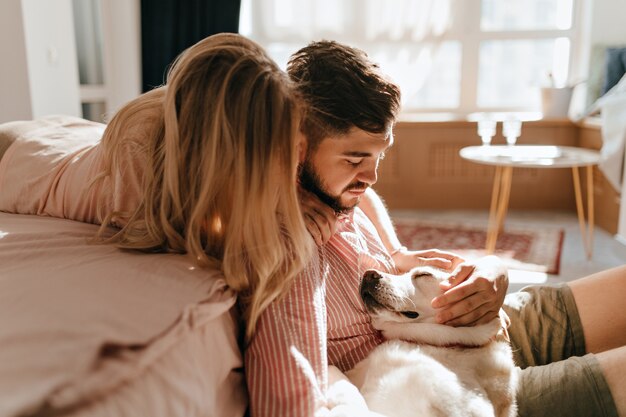 Pareja de enamorados mira a Labrador acostado y durmiendo. Marido y mujer se relajan en un ambiente acogedor.