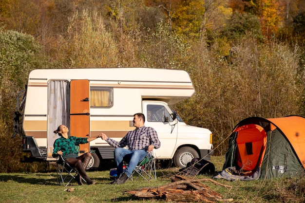 Pareja de enamorados sentados en sillas de camping y disfrutando del hermoso clima. Ambiente romantico