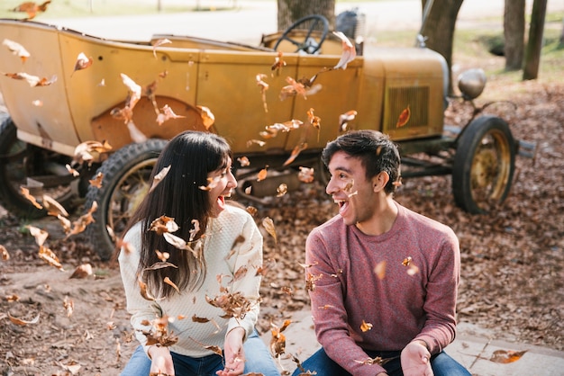 Pareja encantada lanzando hojas de otoño y mirando el uno al otro