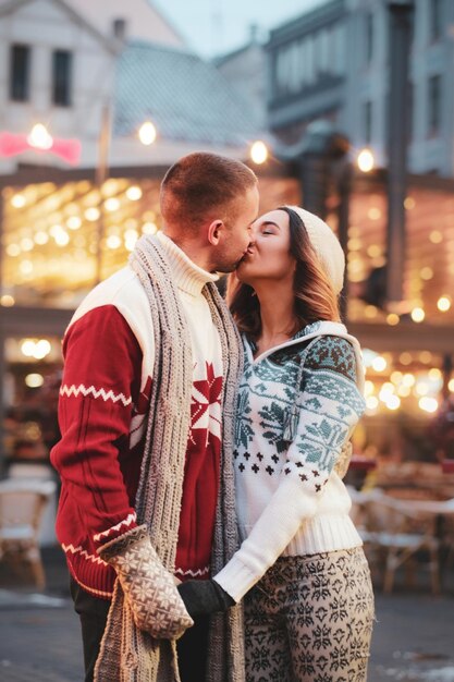 Una pareja encantadora se besa en la calle mientras tienen una cita el día de Navidad.