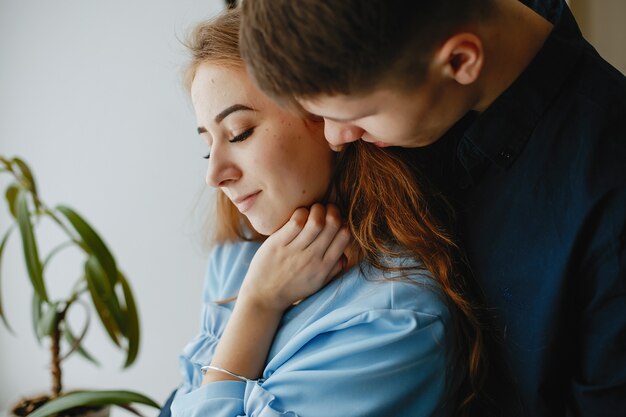 pareja encantadora joven y dulce de pie junto a la ventana en la cocina