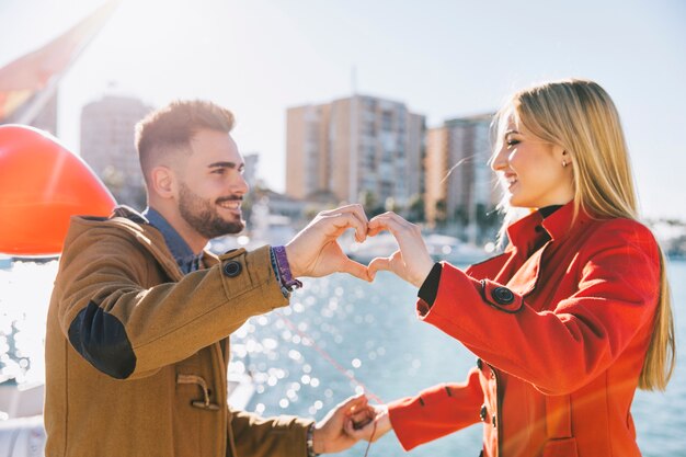 Pareja encantadora mostrando el corazón con las manos