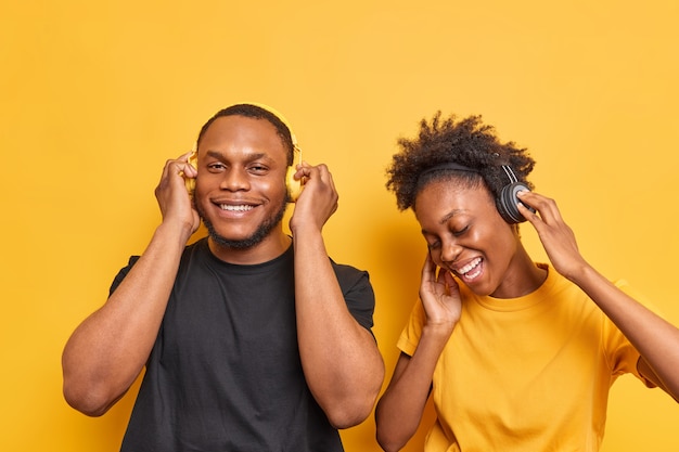 La pareja escucha música, canta su canción favorita, disfruta del tiempo libre vestido informalmente aislado en amarillo vivo