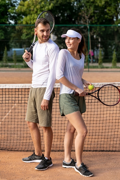 Pareja espalda con espalda en la cancha de tenis