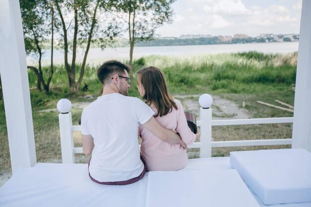 Pareja de espaldas sentada en una cama mirándose a los ojos