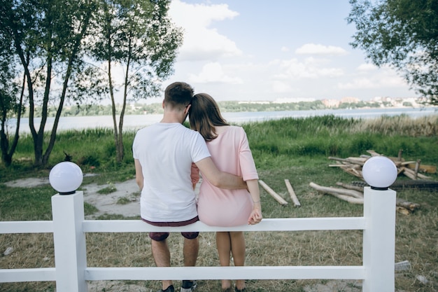 Pareja de espaldas sentada en una valla blanca