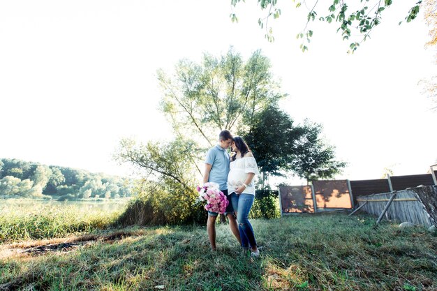 La pareja de espera de moda se encuentra en cálidos abrazos bajo el árbol verde