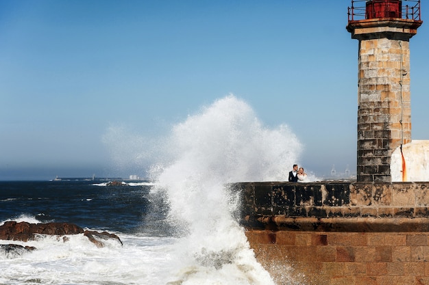 Pareja está mirando el océano parado cerca del faro