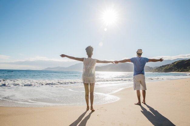 Pareja estirando los brazos en la playa