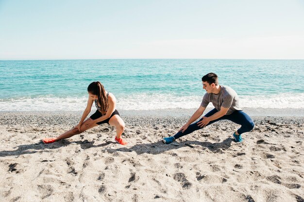 Pareja estirando en la playa