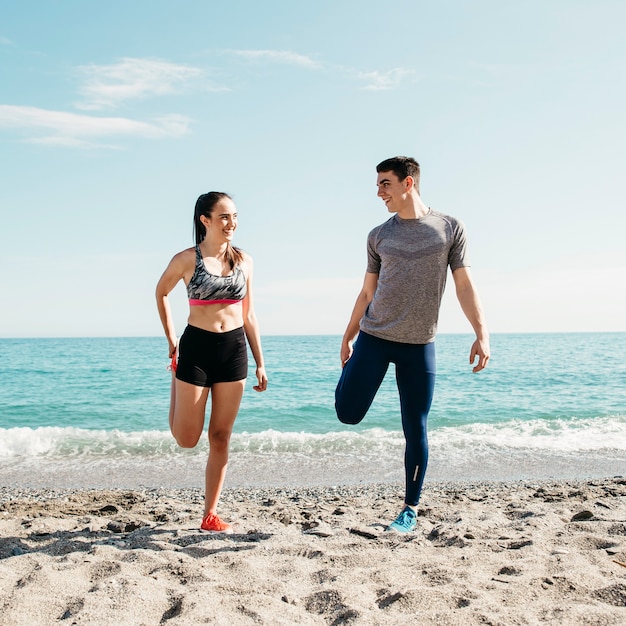 Foto gratuita pareja estirando en la playa