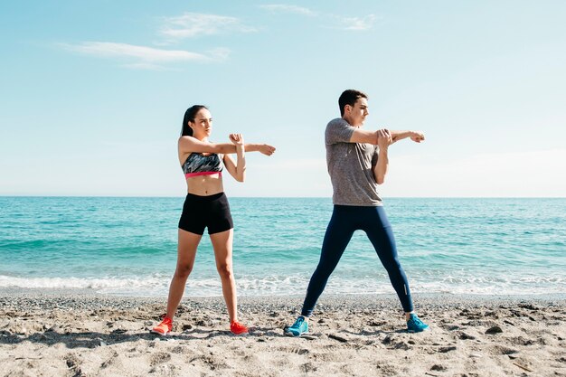 Pareja estirando en la playa