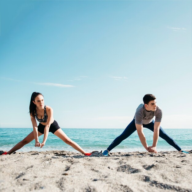 Pareja estirando en la playa