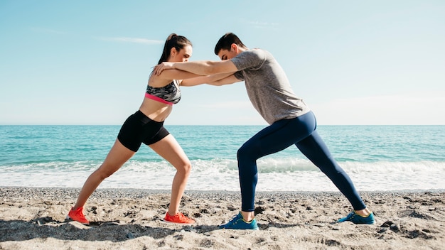 Foto gratuita pareja estirando en la playa