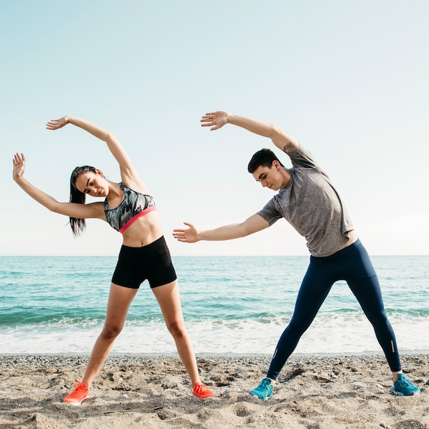 Pareja estirando en la playa