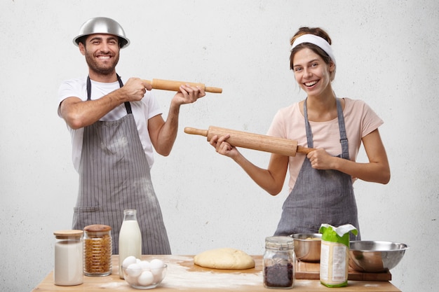 Foto gratuita pareja familiar se hace el tonto en la cocina, se disparan con rodillos de amasar