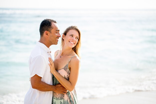 Pareja feliz abrazando en la playa en verano