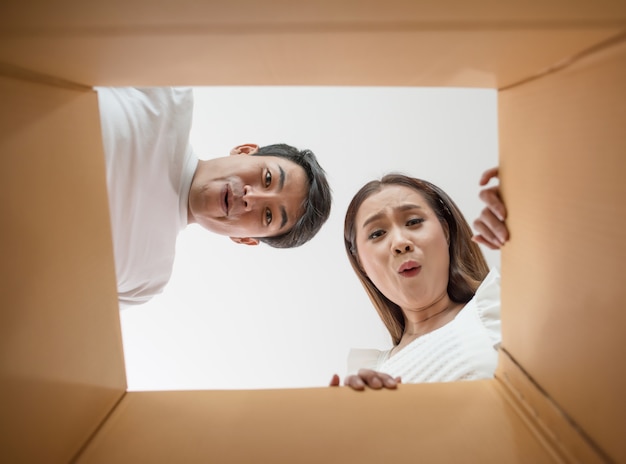 Pareja feliz abriendo una caja y mirando dentro al producto