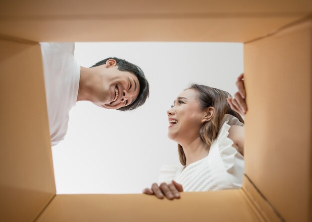 Pareja feliz abriendo una caja y mirando dentro al producto