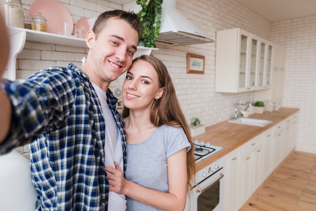 Pareja feliz en el amor haciendo selfie en cocina