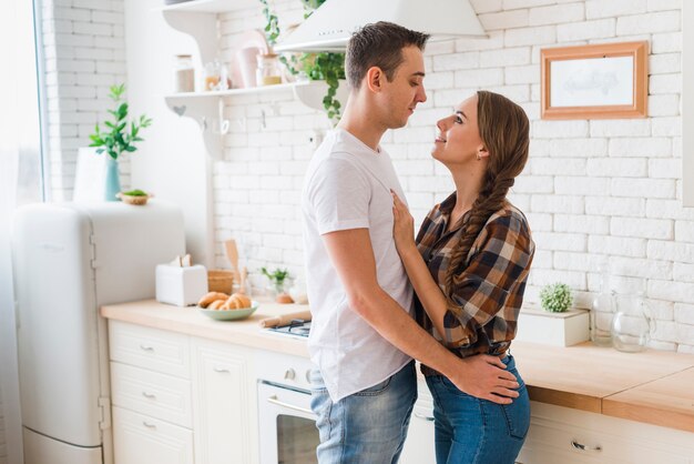 Pareja feliz en el amor juntos abrazos en la cocina