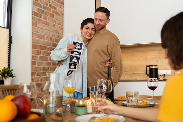 Foto gratuita pareja feliz anunciando el embarazo en una cena con amigos