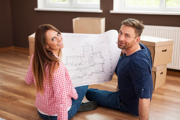 Foto gratuita pareja feliz en apartamento nuevo con plano